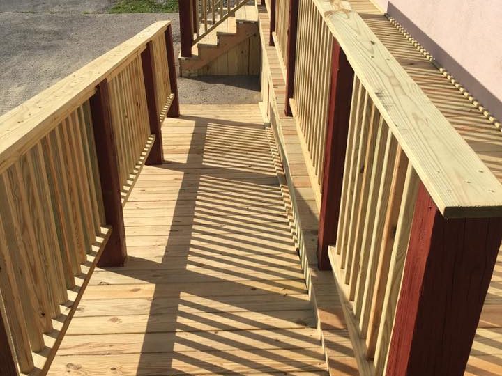 Pressure-treated wood access ramp with red-painted posts and railings at a commercial building in Grayson County, KY