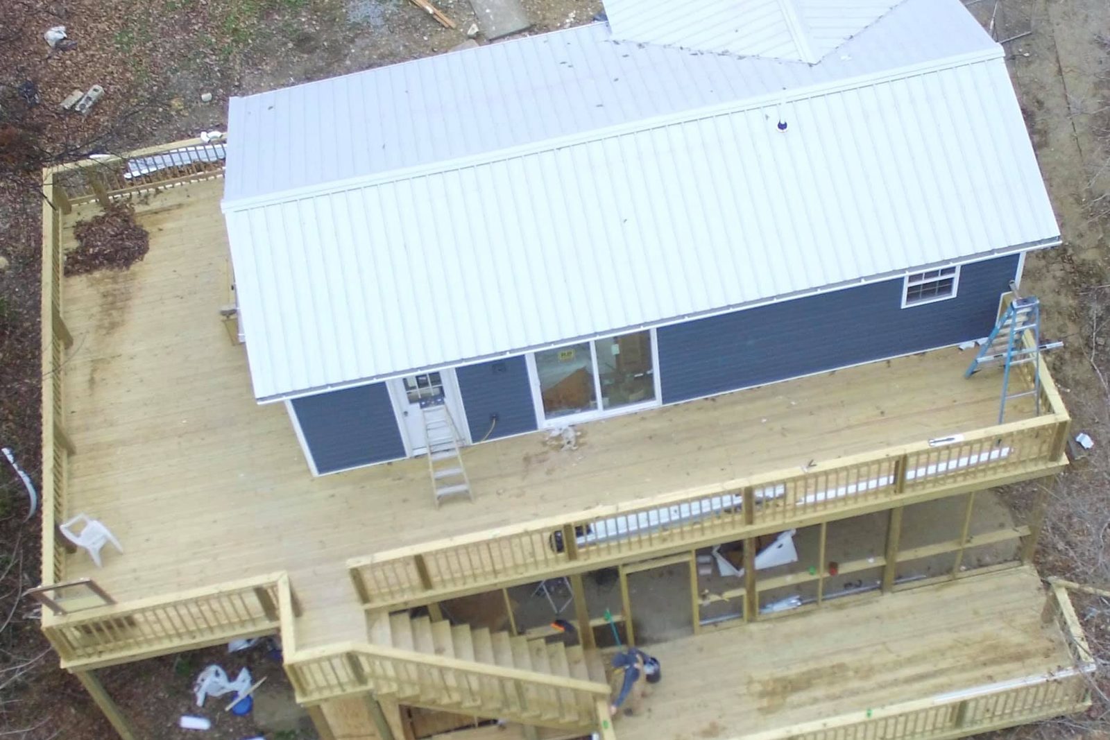 Aerial view of a new multi-level pressure-treated deck at Nolin Lake, KY, wrapping a blue-sided house