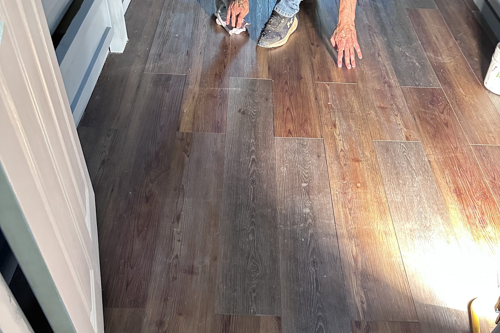 Installer on his knees laying wide vinyl plank flooring in a bedroom in Clarkson, KY