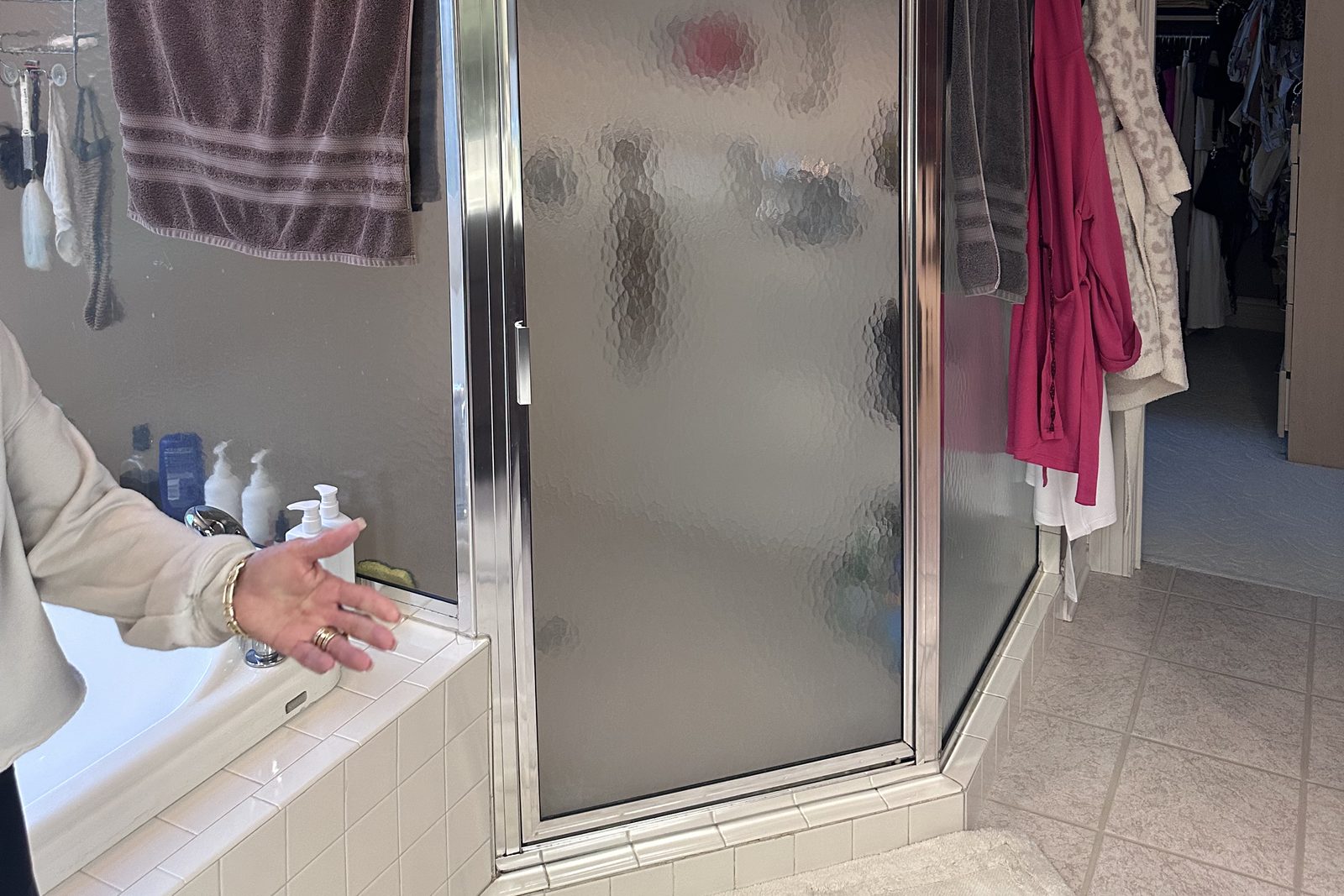 Homeowner pointing out an old framed glass shower stall during an on-site estimate walk-through in Grayson County, KY