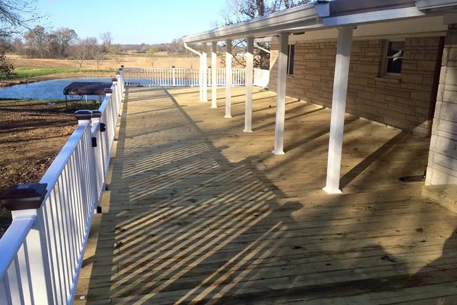 Long covered porch deck with white vinyl railing and square columns, overlooking a pond at Nolin Lake, Kentucky