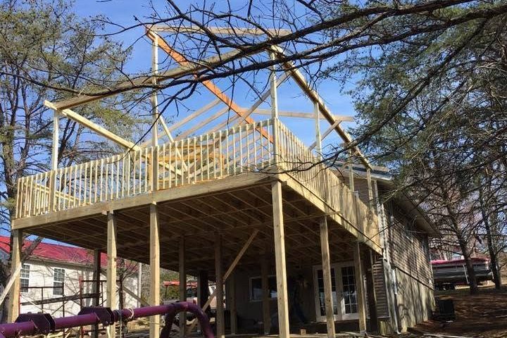 Raised wood deck under construction on tall posts, with roof framing going up — Clarkson, Grayson County, Kentucky