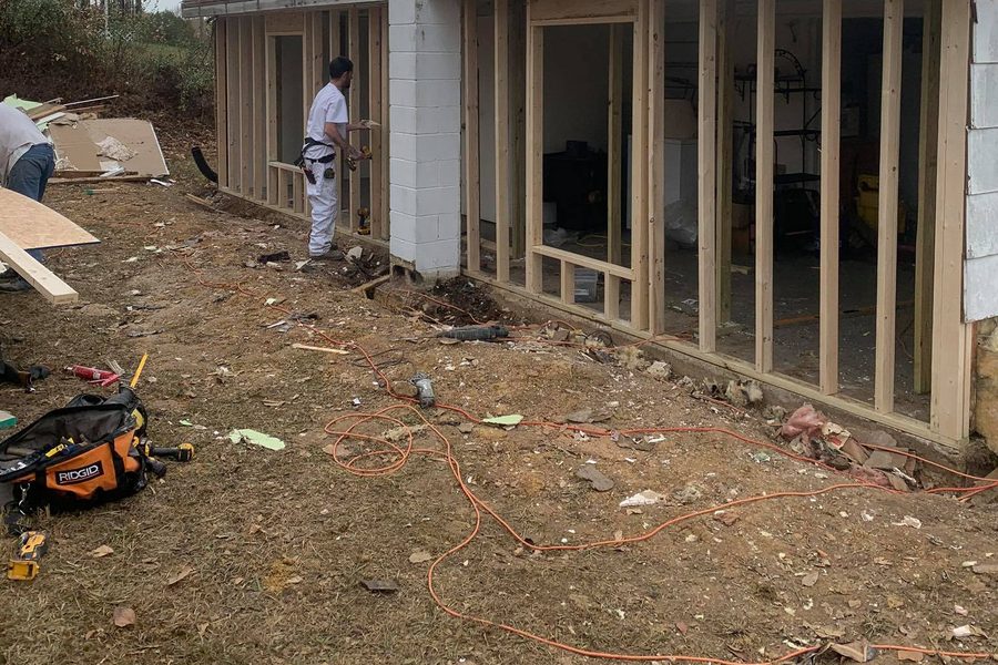 Crew member framing a room addition with a row of new wall studs and window openings at Rough River Lake, Kentucky