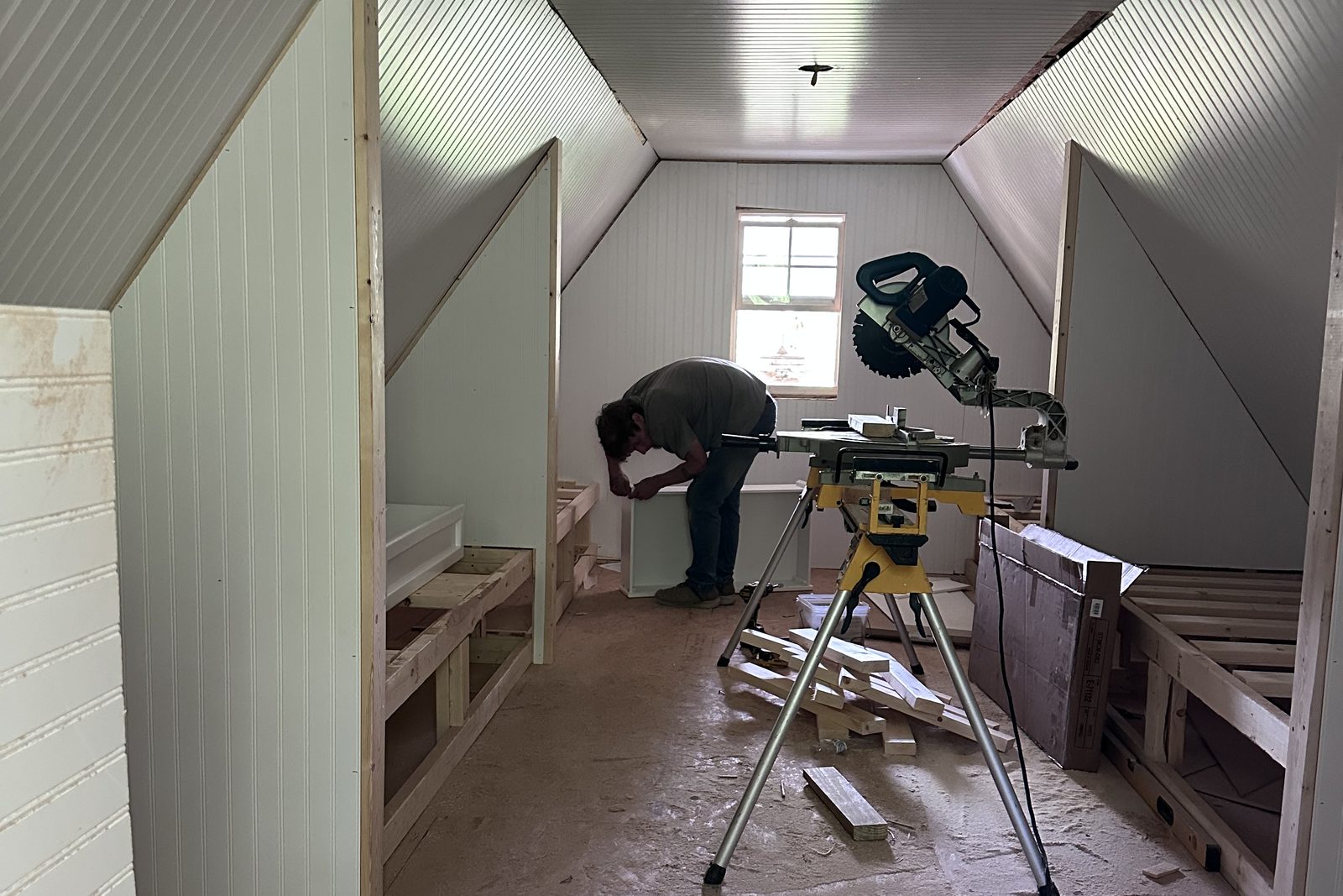 Crew member cutting trim at a miter saw inside an attic room being remodeled — Clarkson and Leitchfield, KY