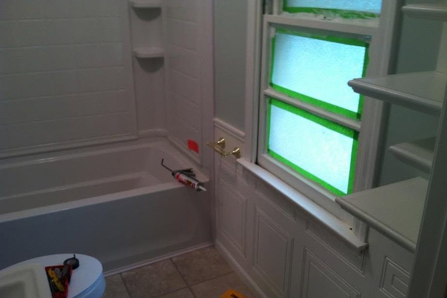 Bathtub and white tub surround being installed during a bathroom remodel, window trim taped off — Clarkson, Grayson County KY